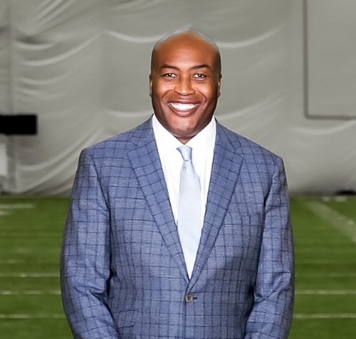 A person in a suit smiling
Description automatically generated